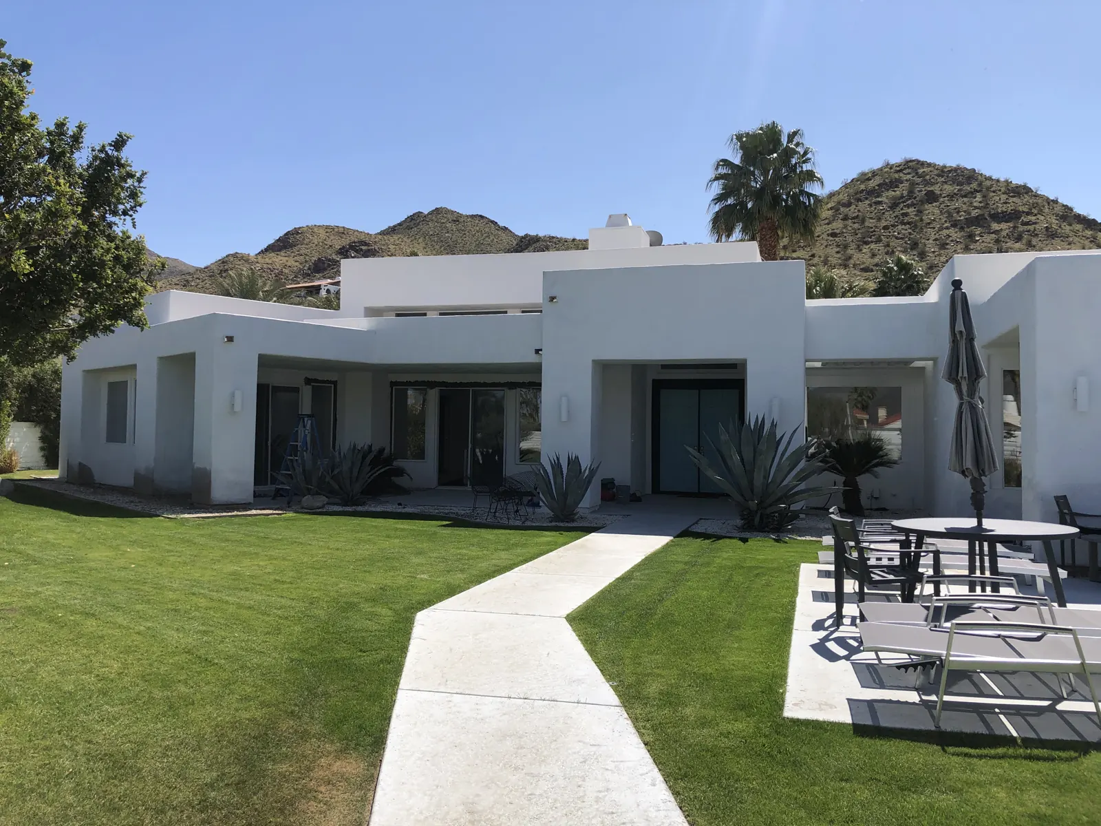 White desert-modern home with new glass doors opening onto the lawn